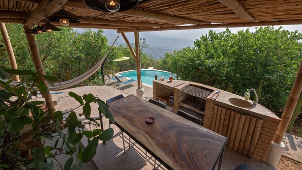 Un espacio al aire libre techado con piscina, barbacoa y zona de estar.