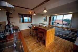 A kitchen with a wooden countertop, bar stools, and a view through large windows. - Utopia Casa Horizonte: a house with a view, and all you need.   (Oaxaca de Juarez)