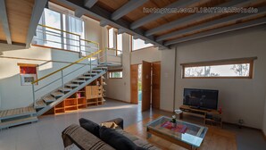 Amplia sala de estar con escaleras, un sofá, una mesa de centro y un televisor.