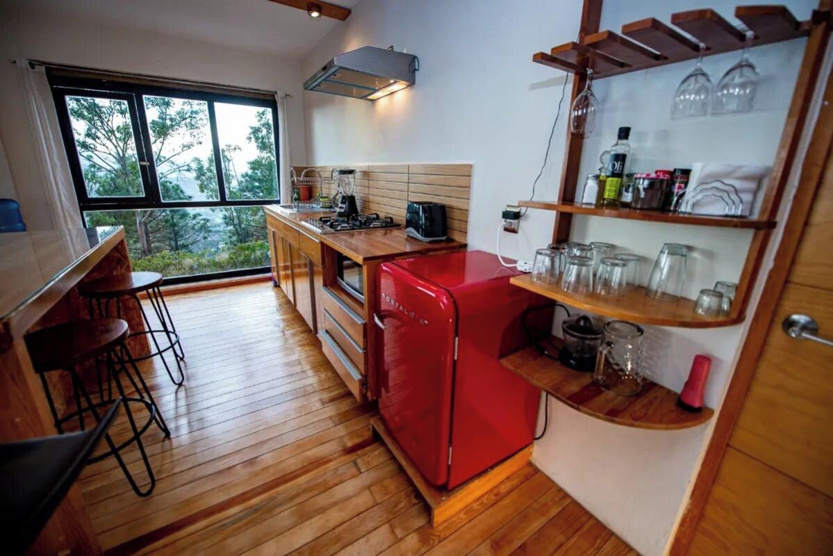 A compact kitchen with a red refrigerator, wooden countertops, and a window overlooking greenery.