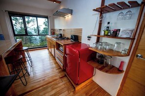 A compact kitchen with a red refrigerator, wooden countertops, and a window overlooking greenery. - Utopia Casa Horizonte: a house with a view, and all you need.   (Oaxaca de Juarez)