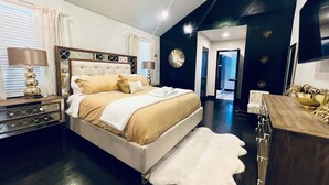A modern bedroom with a large bed, a nightstand, a dresser, and a white shag rug. - Elegant NW Atlanta Oasis, 2 Kitchens, Sauna, Billiards, Patio, Sundeck & Yard! (Atlanta)