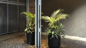 Un área pavimentada con ladrillos, dos macetas y una estructura metálica.