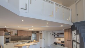 Cocina moderna con una isla central, electrodomésticos integrados y un rincón comedor con un sofá de tonos claros.