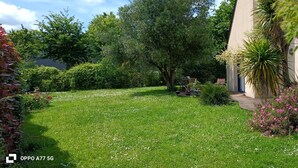 A well-maintained garden with a lawn, various shrubs, and a pathway leading to a building.