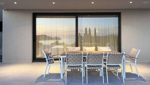 An outdoor dining area with a table and chairs, large windows, and a view of the cityscape.