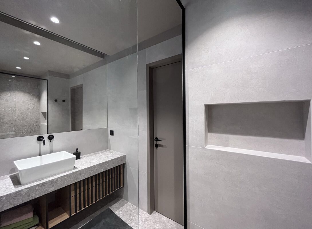 Une salle de bain moderne avec un grand miroir, un lavabo rectangulaire et un espace douche.