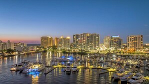 A marina with multiple boats docked, surrounded by high-rise buildings with illuminated windows. - Perfect location Walk to the village and beach Private Balcony Heated Pool (Siesta Key)