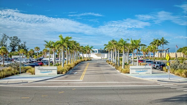 A parking lot with multiple cars and a pedestrian crossing sign. - Perfect location Walk to the village and beach Private Balcony Heated Pool (Siesta Key)