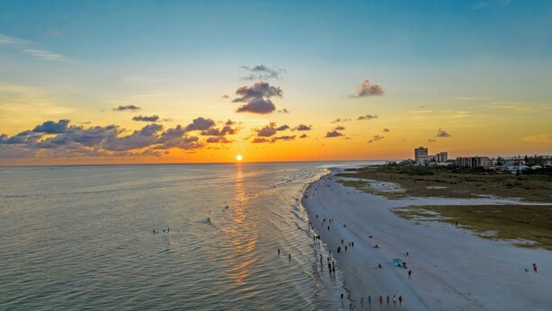 A beach with a sunset, a sandy shore, and buildings in the background. - Perfect location Walk to the village and beach Private Balcony Heated Pool (Siesta Key)