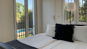 Un dormitorio con cama, ventana y vista a una piscina.