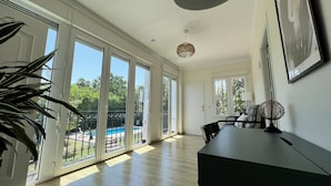 Una habitación amplia con grandes puertas de vidrio correderas que dan a un balcón, una mesa de comedor y una lámpara colgante.