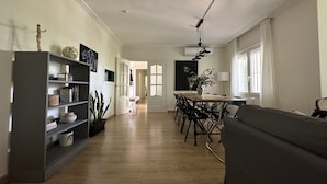 Un salón espacioso con una mesa de comedor y sillas, una estantería y un sofá.