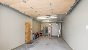 A hallway with a wooden door, a trash bin, and a glass door. - Spacious Ski-In/Ski-Out Retreat (Big Sky)
