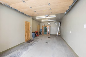 A hallway with a wooden door, a trash bin, and a glass door. - Spacious Ski-In/Ski-Out Retreat (Big Sky)