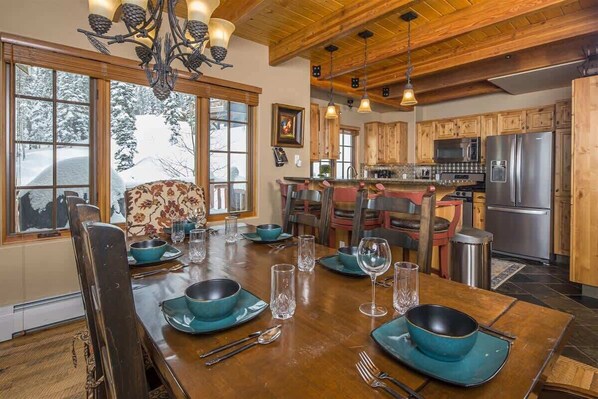 A dining area with a wooden table set for four, surrounded by wooden chairs. - Spacious Ski-In/Ski-Out Retreat (Big Sky)