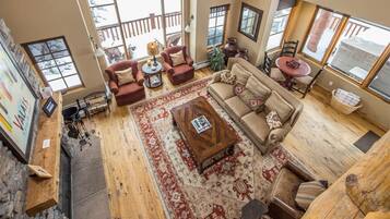 A spacious living room with a large window, a red patterned rug, and a wooden coffee table.