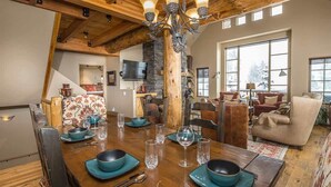 A dining area with a wooden table set for four, surrounded by chairs. - Spacious Ski-In/Ski-Out Retreat (Big Sky)