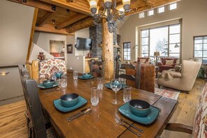 Un coin repas avec une table en bois, dressée pour quatre personnes, entourée de chaises.
