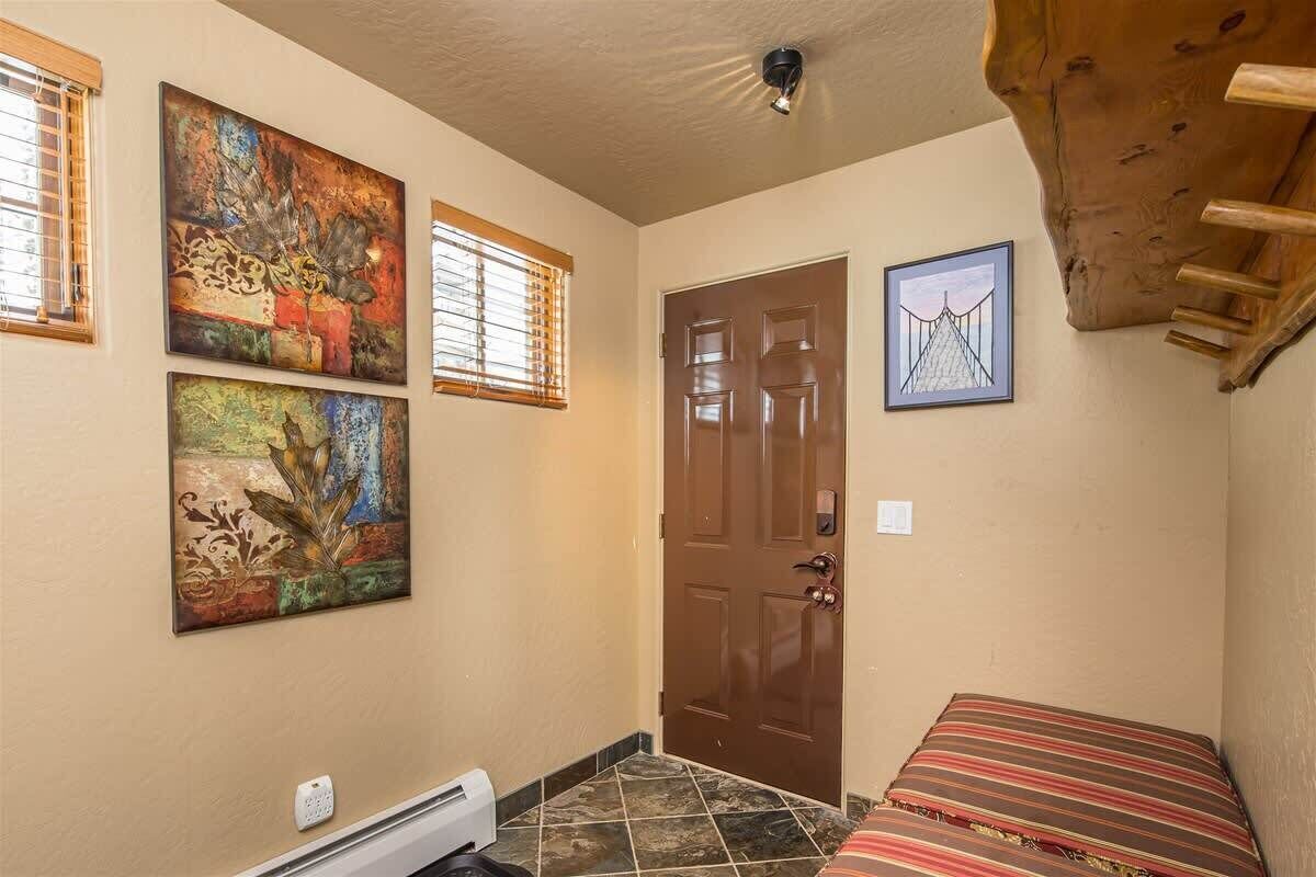 A room with a bed, a door, and two windows. There are two paintings on the wall.