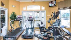 A gym with treadmills, elliptical machines, and a TV screen. - Sun Key Resort Townhouse🏝 10 min from Disney (Kissimmee)