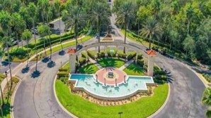 A landscaped area with a central fountain, surrounded by palm trees and a curved road. - Sun Key Resort Townhouse🏝 10 min from Disney (Kissimmee)