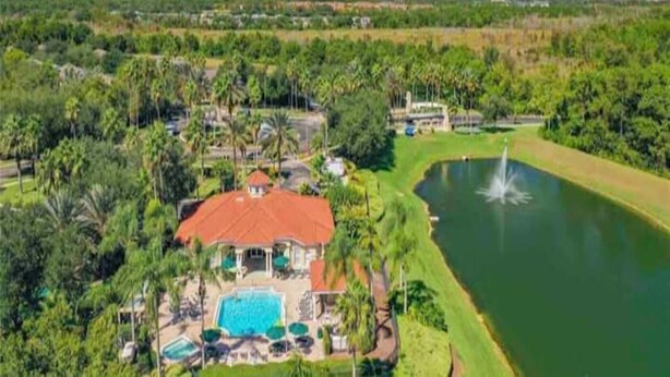 A large house with a swimming pool, surrounded by lush greenery and a lake. - Sun Key Resort Townhouse🏝 10 min from Disney (Kissimmee)