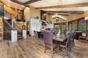 Une cuisine spacieuse dotée d’un grand îlot central, de planchers en bois et d’un escalier menant à un niveau supérieur.