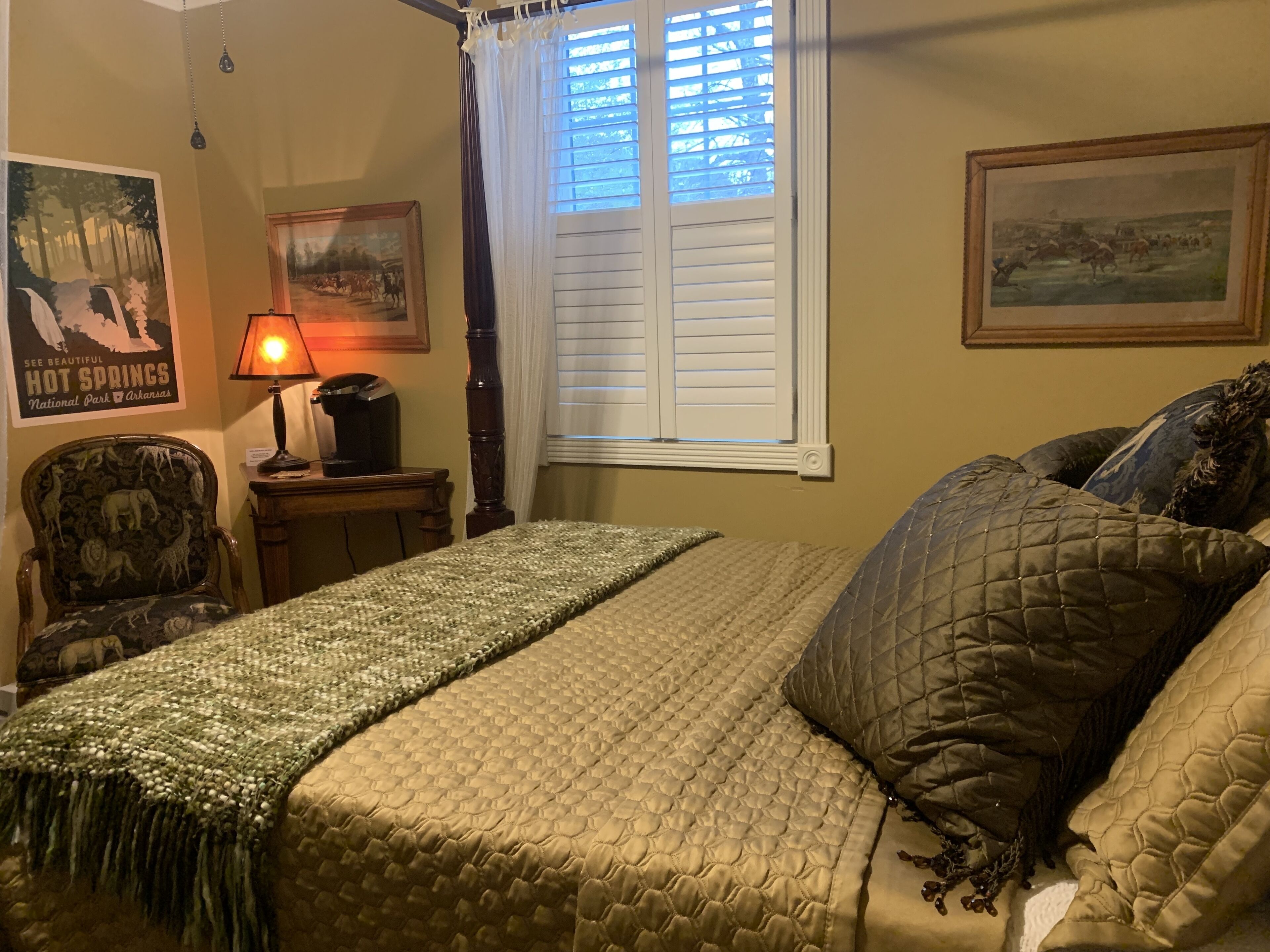 Un dormitorio con cama, una silla, una lámpara y una ventana con persianas.
