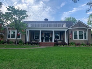 Ein zweistöckiges Haus mit Veranda, Schornstein und einer amerikanischen Flagge.