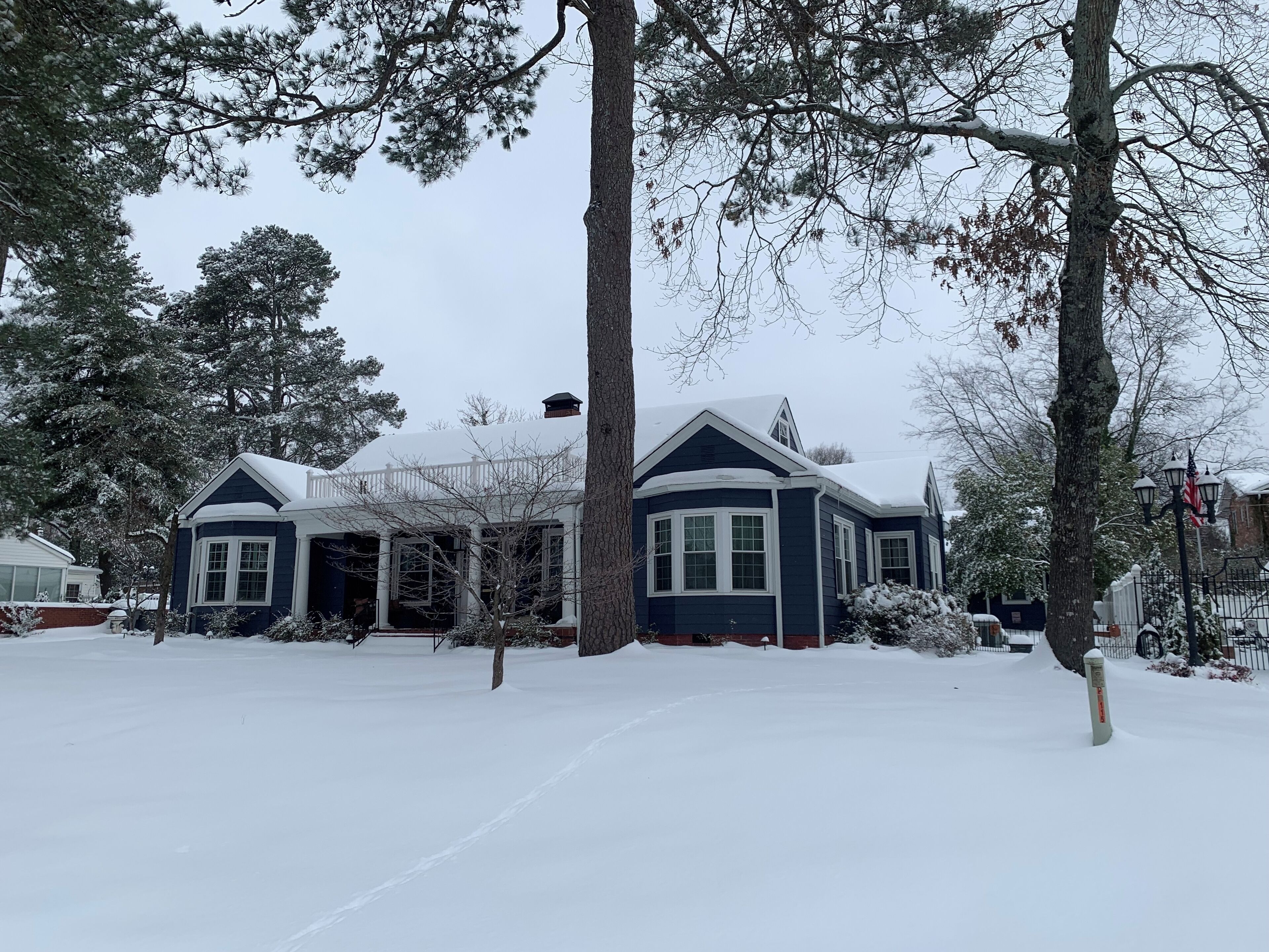 A two-story house with a snow-covered roof and a porch.