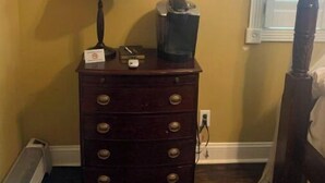 Un aparador de madera con cajones, una lámpara, un televisor y un cuadro en la pared.