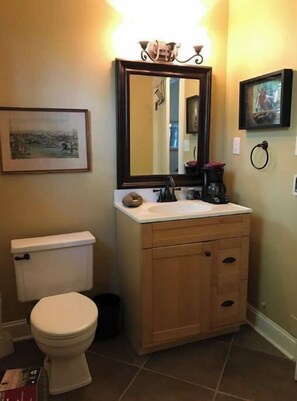 A bathroom with a toilet, sink, vanity, and a mirror.