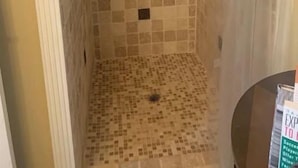 Un pequeño baño con paredes y piso de azulejos, un cabezal de ducha y una cortina de baño.