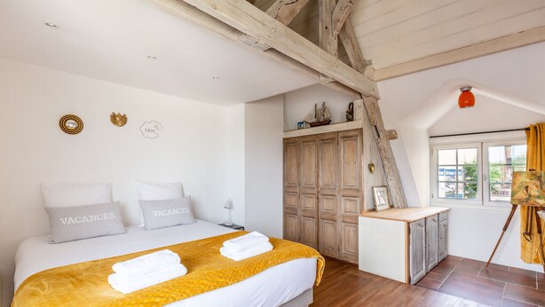Une chambre à coucher avec un lit, une armoire en bois et une fenêtre avec des rideaux.