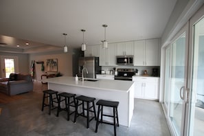 A modern kitchen with white cabinets, stainless steel appliances, and a central island with bar stools.
