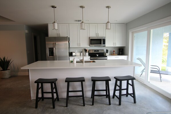 A modern kitchen with white cabinets, stainless steel appliances, and a central island with bar stools.
