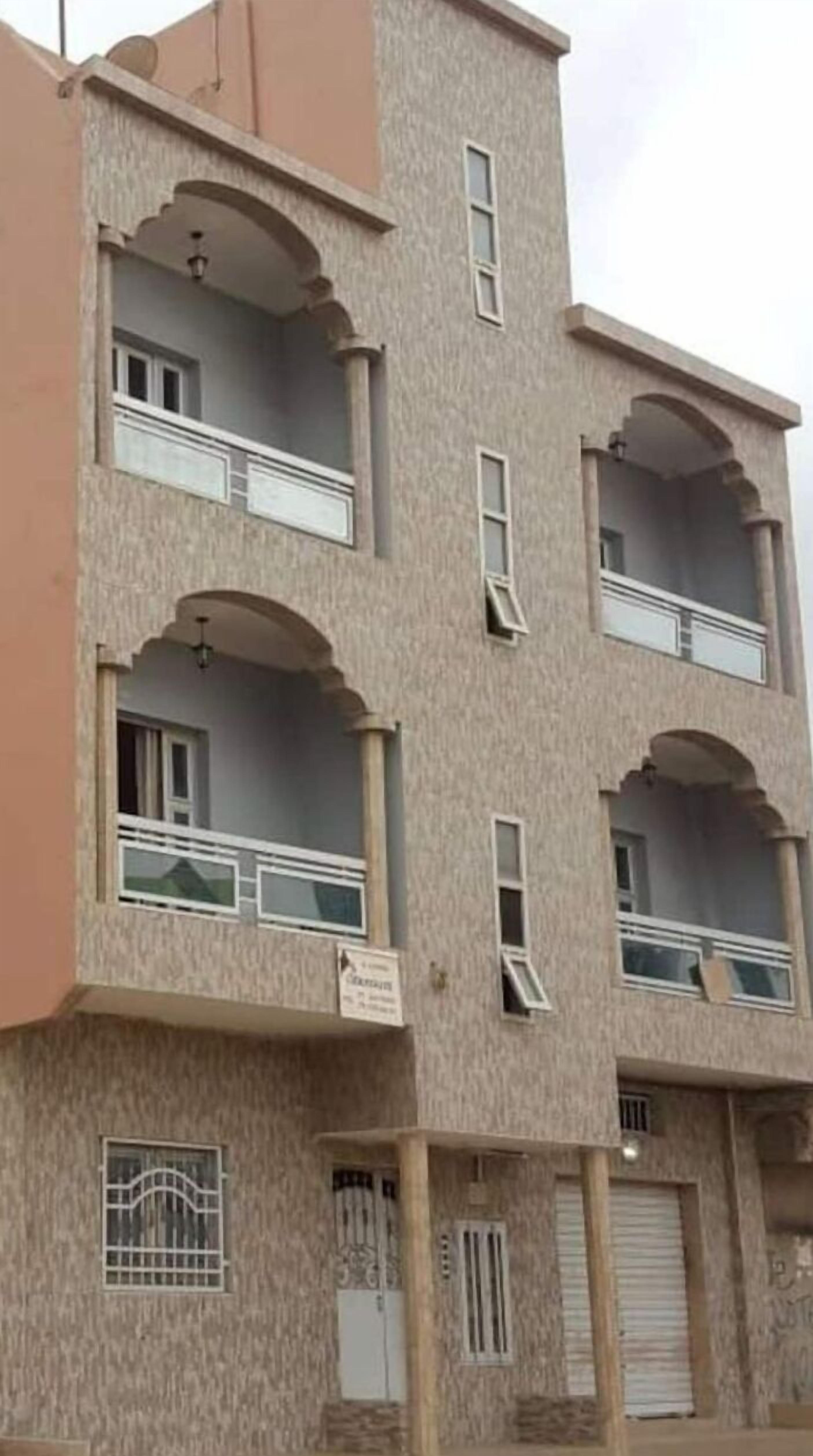 A multi-story building with balconies, a flat roof, and a sign indicating 'No Parking.'