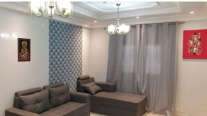 A living room with a sofa set, patterned wallpaper, a chandelier, and a red artwork on the wall. - Designer apartment (Dakar)