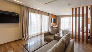 Une chambre d’hôtel moderne équipée d’un grand téléviseur à écran plat, d’un canapé, d’une table basse et d’une cloison en bois.