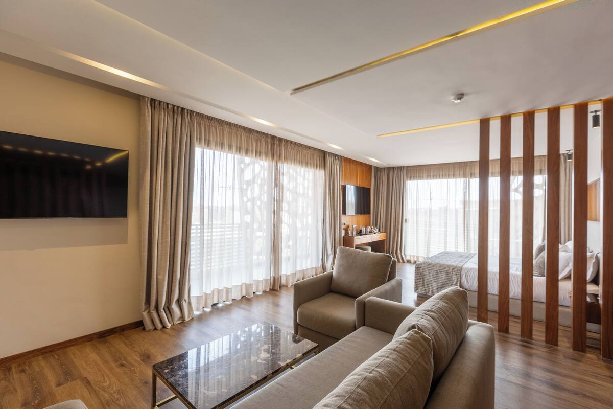 Una habitación de hotel moderna con un televisor de pantalla plana grande, un sofá, una mesa de centro y un panel de madera.