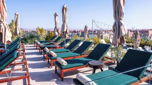 A rooftop terrace with rows of sun loungers and umbrellas, offering a view of a cityscape. - Longue Vie Hôtels (Marrakech)
