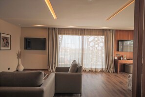 A modern living room with a sofa, a flat-screen TV, and a dining area with a wooden table and chairs. - Longue Vie Hôtels (Marrakech)