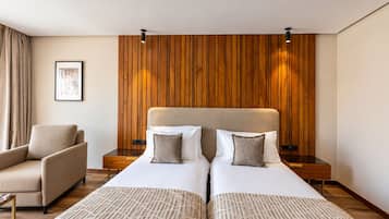 A hotel room with two beds, a sofa, wooden paneling on the wall, and a framed picture on the wall.