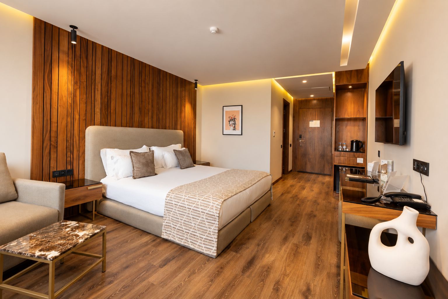 Una habitación de hotel moderna con una cama grande, un escritorio, una silla y un televisor.
