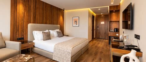 Una habitación de hotel moderna con una cama grande, un escritorio, una silla y un televisor.