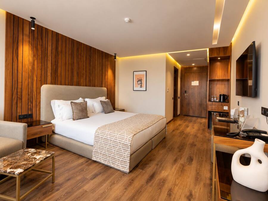 Habitació d'hotel moderna amb un llit gran, una taula de treball, una cadira i una televisió.