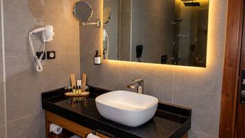 Un baño moderno con un espejo grande, un lavamanos blanco y un mueble de tocador con toallero.