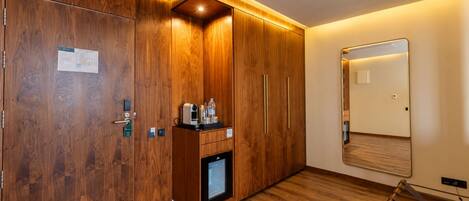 Habitación de hotel con paneles de madera, un minibar, un espejo y suelo de madera.