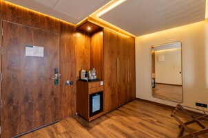 Una camera d'albergo con pannelli in legno, un minibar, uno specchio e un pavimento in legno.